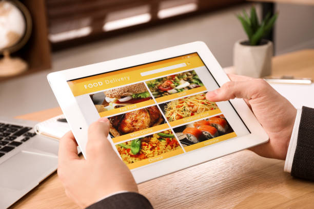 istock Man using tablet for ordering food online at work, closeup. Concept of delivery service 1456607019