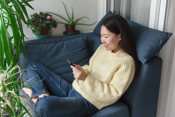 istock Young woman using a smartphone while sitting on the sofa 1456607927