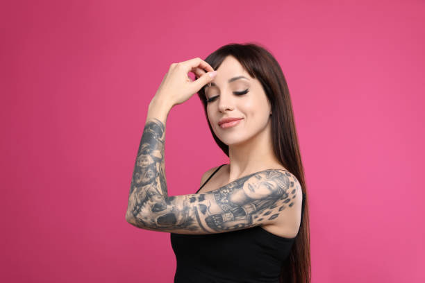 istock Woman with tattoos on arm against pink background 1456608024