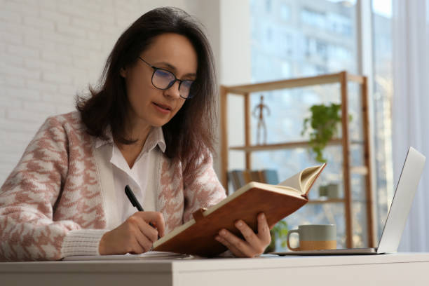 istock Woman with modern laptop and notebook learning at home 1456609804