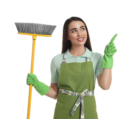 Beautiful young woman with broom on white background