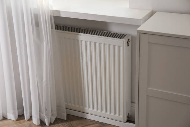 istock Modern radiator on white wall near window indoors 1456611890