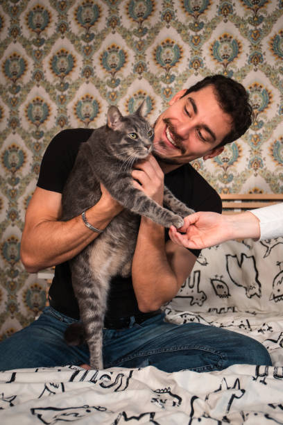 istock The young man is playing with his cat on the bed. 1456612050