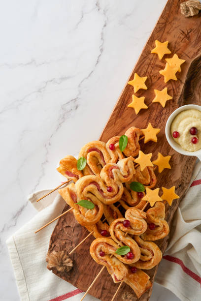 istock Christmas or New Year appetizer. Christmas tree shape puff pastry buns with cheese and ham. Group of Christmas tree shapes on wooden board. Festive idea for Christmas or New Year dinner. Top view. 1456612420