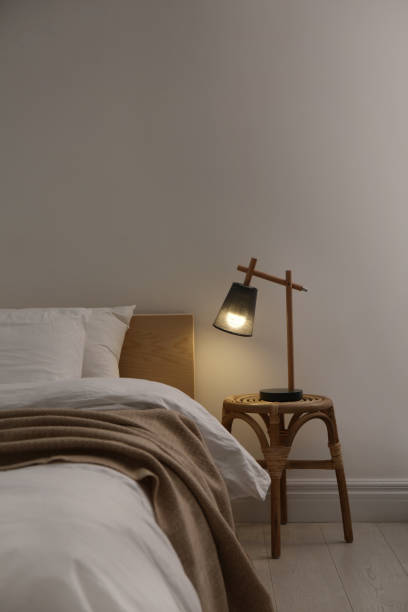 istock Stylish lamp on table near bed indoors 1456612442