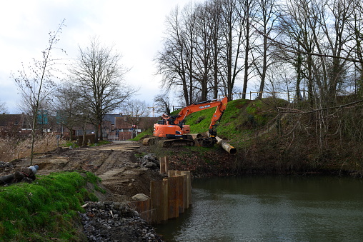 Diest, Flemish-Brabant, Belgium - January 15, 2023: on Sunday stationary orange excavator DX 235 next to a pond and a retaining wall nature improvement works