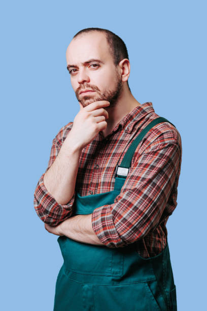 istock Pensive, serious young male employee in overalls captured, 1456619507