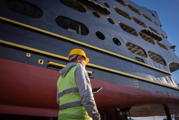 un technicien vérifie les travailleurs qui réparent un traversier de croisière en cale sèche - construction built structure building activity shipyard photos et images de collection