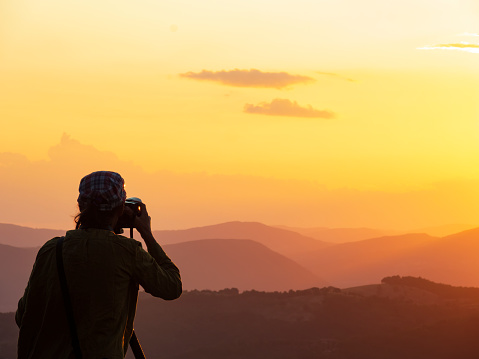 Photographer with tripod takes photos of a beautiful sunset in Umbria, Italy