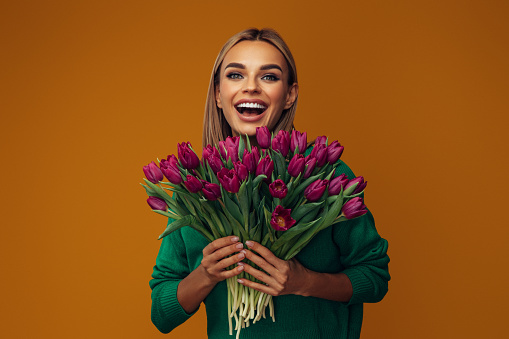 Beautiful emotional woman holding bouquet of flowers