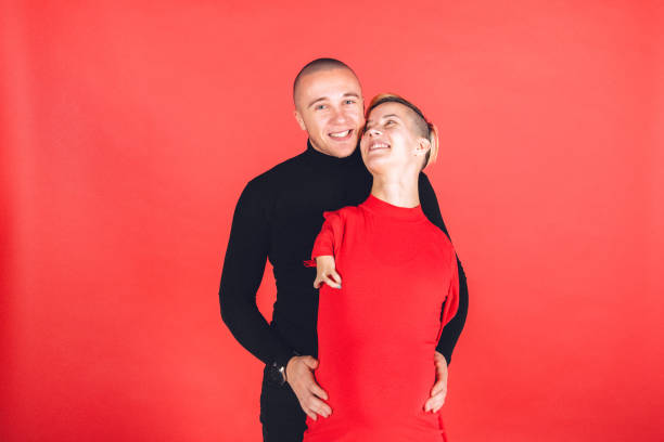 Young pregnant female adult with disability and her young male partner in studio portraiture.