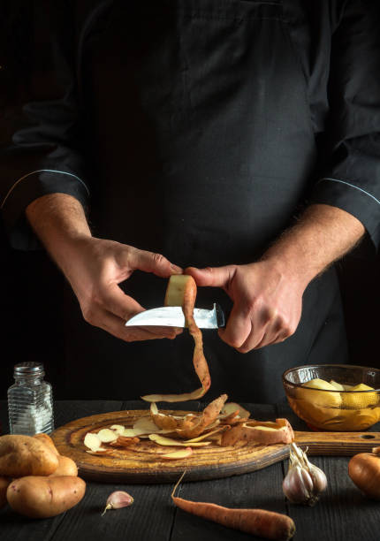 istock The chef peels raw potatoes in a restaurant kitchen before preparing a national dish. Close-up of a cook hands with a knife while working 1456630962