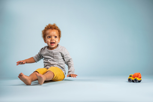 Portrait Of A Young Toddler Playing On The Floor In The Studio