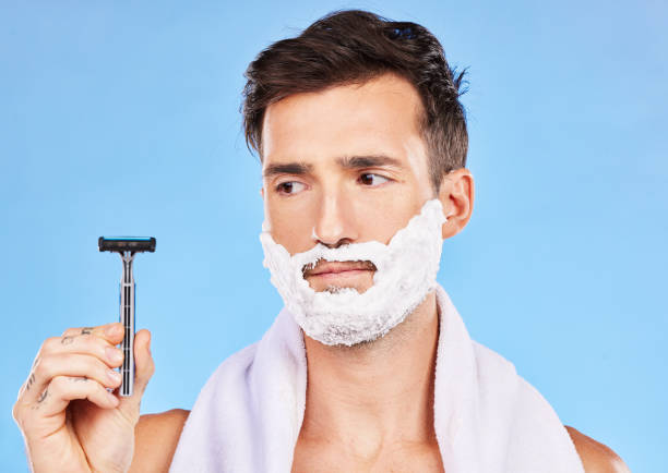 istock Man doubt, shave and face in studio with razor, thinking or cosmetics for self care, beauty and foam. Grooming, facial health and skincare with shaving cream, beard and contemplating in bathroom 1456636505