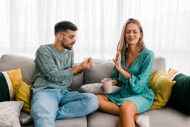 foto de una pareja joven teniendo una discusión en casa - discusión fotografías e imágenes de stock