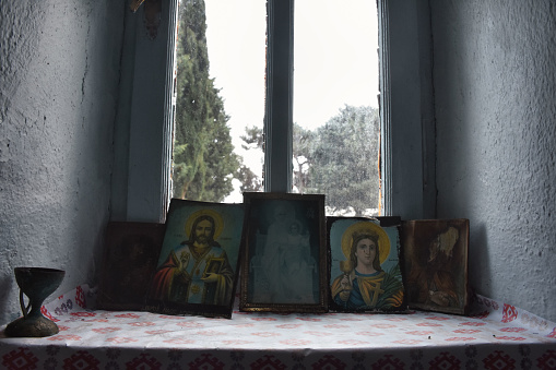 Religious icons fronf of window in a small Greek Orthodox chapel of Gökçeada,  Jesus, saints icons. Canakkale Turkey. Imbros Island. November 29, 2019
