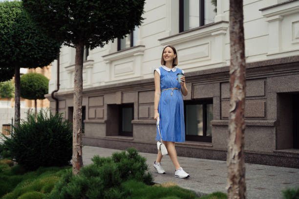 Pregnant woman walking through the city in a blue dress stock photo