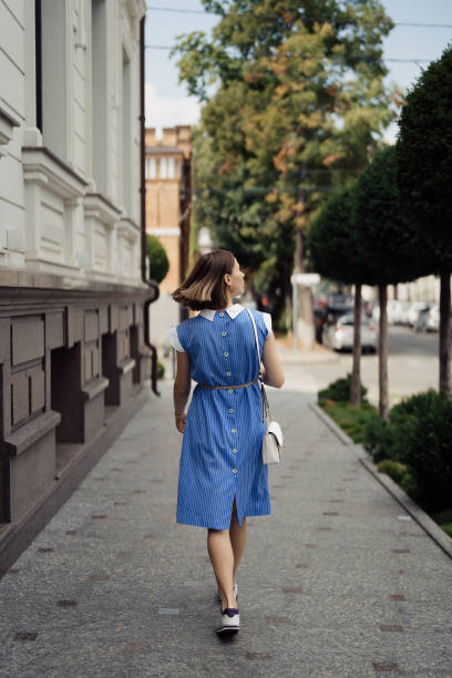 Woman in a blue dress walking on the city street stock photo