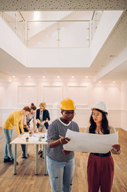 istock Portrait of two multiracial architect looking at blueprints in an office 1456643932
