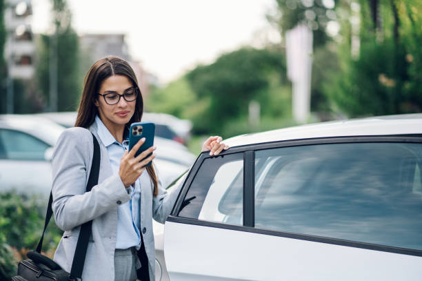 istock Business woman getting into the car and using smartphone 1456643937