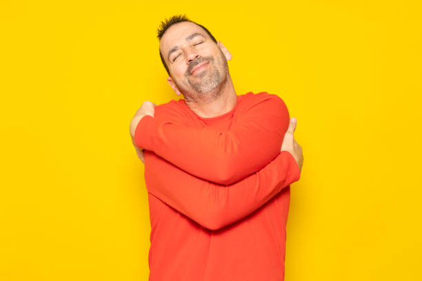 istock Bearded hispanic man completely excited and self-absorbed hugging himself showing he loves himself very much isolated over yellow background. 1456644190