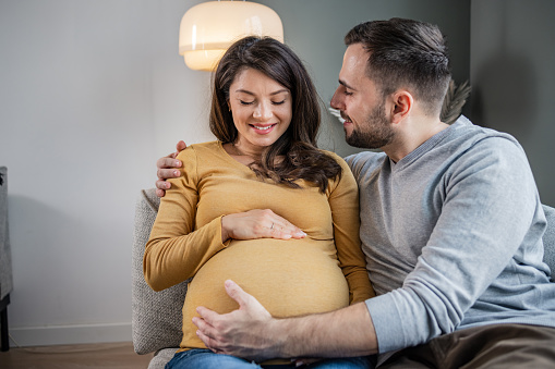 New parents enjoying pregnancy touching belly at home