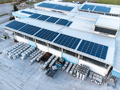 Aerial view of solar panels on the roof of a large storage facility, factory. Providing electricity for the facility, self sufficient facility. Solar panel installation on the roof of a factory.