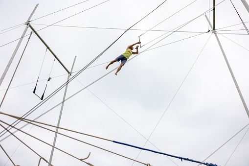 Mature female trapeze artist flying in the sky