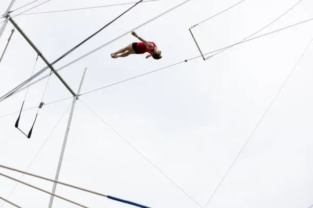 Mature female trapeze artist flying in the sky