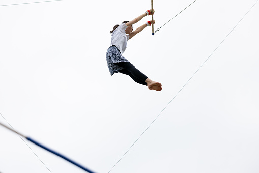 Young female trapeze artist flying in the sky