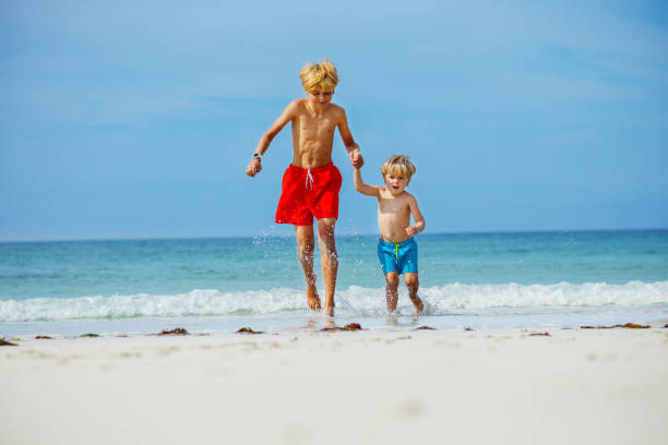 istock Two happy boys run on the sand beach holding hands 1456659408