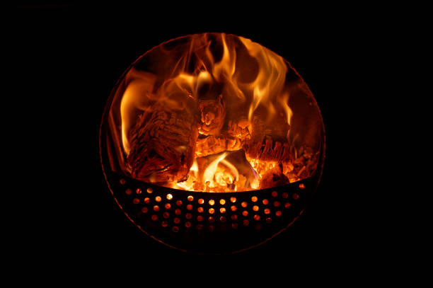burning and glowing logs in a fireplace stove with round window