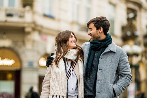 Happy couple embracing and walking on city street on a winter day in Prague.