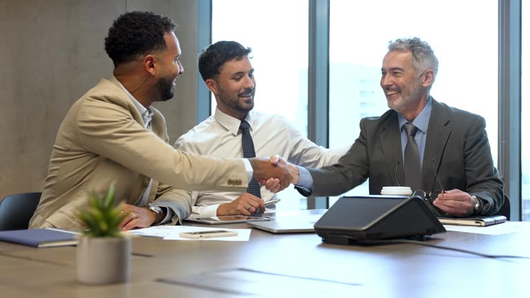 Three businessmen meeting and shaking hands in a conference room.