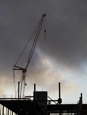 Low angle view of crane at a construction site during sunset