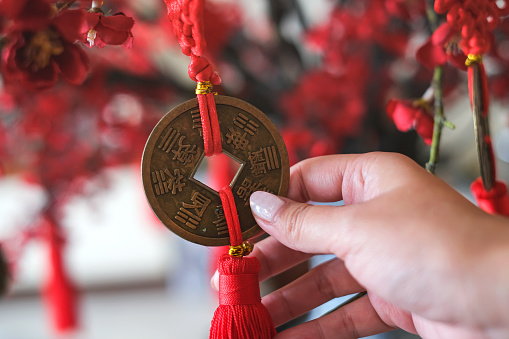 Close-up shot of unrecognizable female hand holding gold coin pendant during Chinese new year