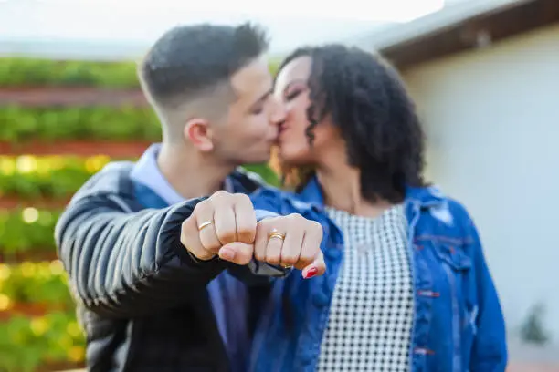 Loving couple in love kissing and showing wedding ring in hand