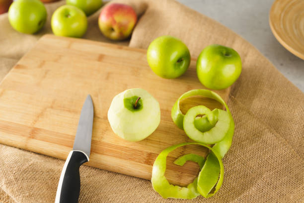 Green apple peeled close-up on a wooden board on a kitchen table, view from above. Green and red apples close-up
