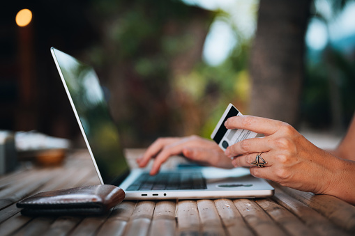 Female hands holding credit card and typing on laptop keyboard