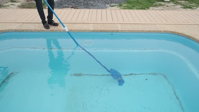 Man cleans the pool with a portable vacuum cleaner. Preparing and cleaning the pool for the swimming area