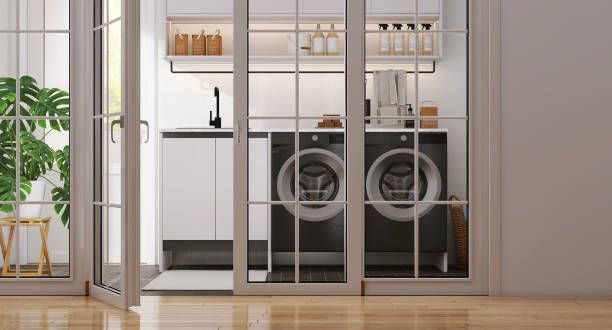 istock Modern design white frame glass panel lite door of laundry room with two black washing machine, cabinet, cupboard, sink, monstera plant and tile floor 1456697073