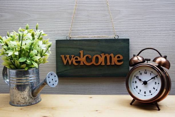 istock Welcome Sign with alarm clock on wooden background 1456699230