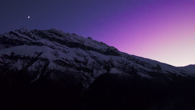 Amazing night landscape with a snow-capped mountain peak against the purple sky