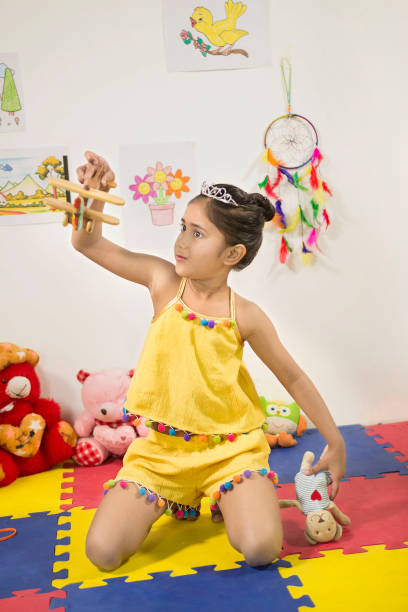 王冠をかぶったかわいいインドの女の子がおもちゃの飛行機で遊んでいる - wall decor ストックフォトと画像