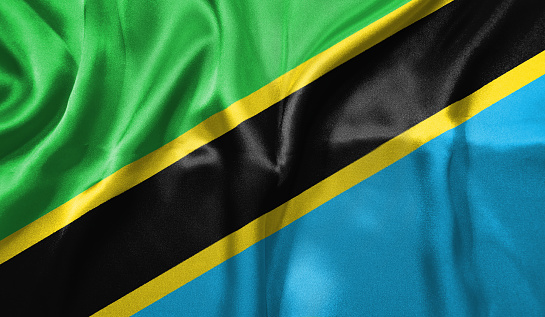 Tanzania flag wave close up. Full page Tanzania flying flag. Highly detailed realistic 3D rendering.