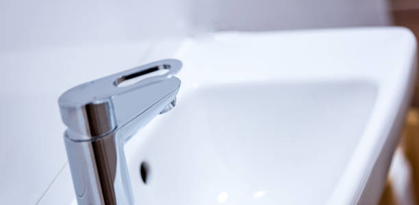 istock Open chrome faucet, tap washbasin in light room 1456711900