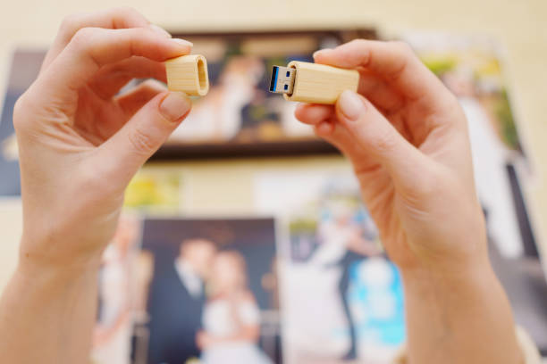 selective focus. printed wedding photos, wooden box and hands with flash drive selective focus. printed wedding photos, a wooden box and hands with a flash drive. the concept of preserving the memory of an important event, the services of a professional photographer. usb stick photos stock pictures, royalty-free photos & images