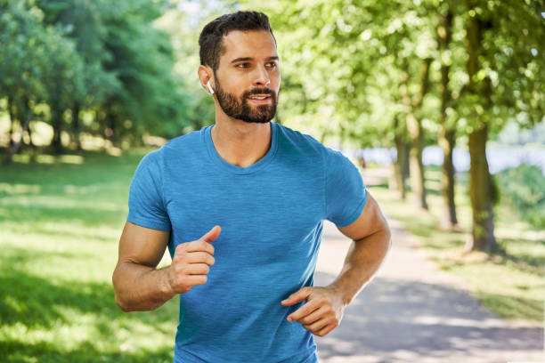 istock Handsome young man running in park during spring summer 1456714055