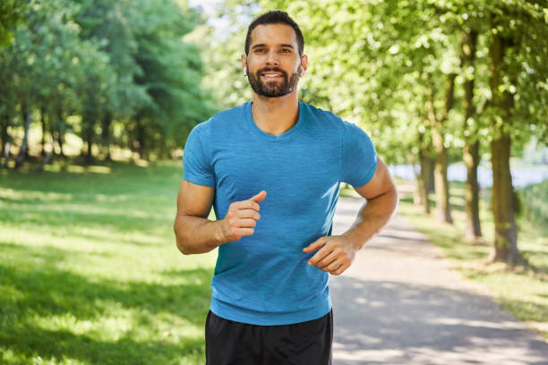 Smiling man running in park at sunny summer day stock photo