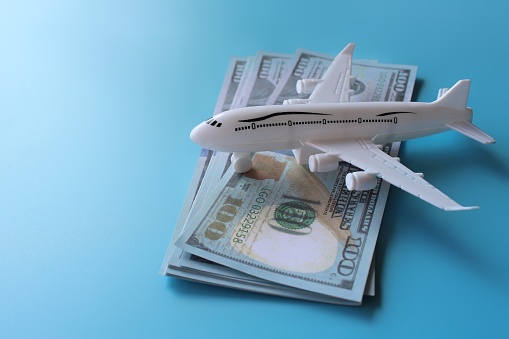 Toy plane and money on blue background with copy space